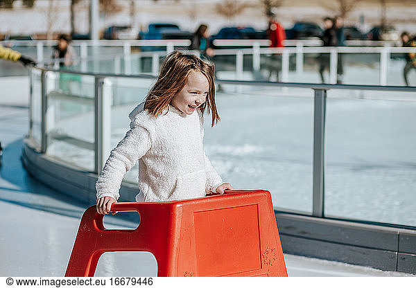 young girl learning how to ice skate on a sunny winter day