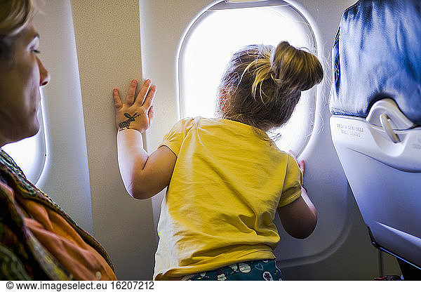 Young girl looking out of the window of an airplane