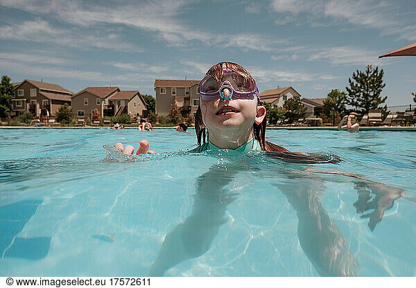 Young girl looking up in pool on sunny day