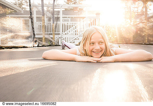 Young Girl Lying on Trampoline on Sunny Evening