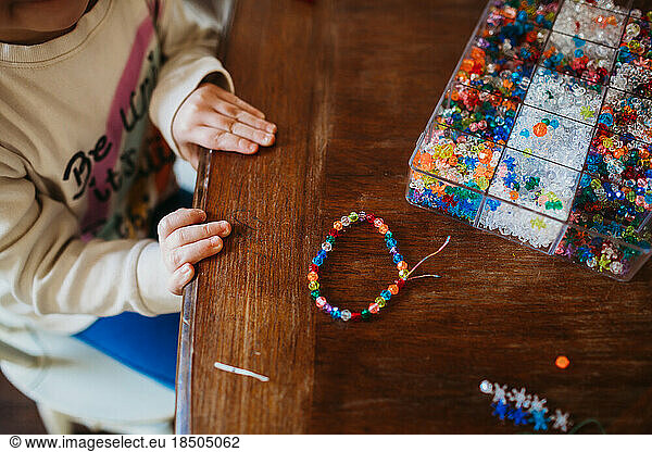 Young girl making colorful bracelet at home