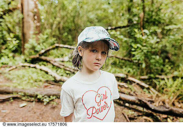 Young girl on a hike in the woods of Hawaii wearing girl power shirt