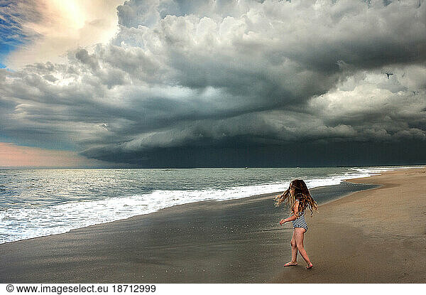 Young girl on the beach under stormy sky