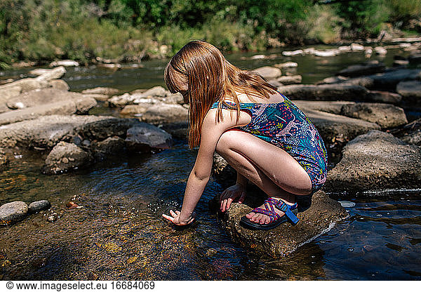 Young Girl playing in a shallow stream on a sunny summer day