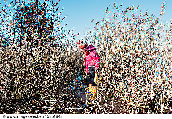 young girl playing in long grass by the beach in winter