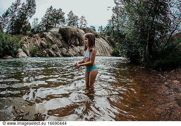 Young Girl playing in river wearing a bathing suit