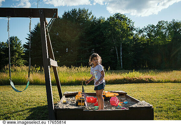 Young girl playing outside in sandbox