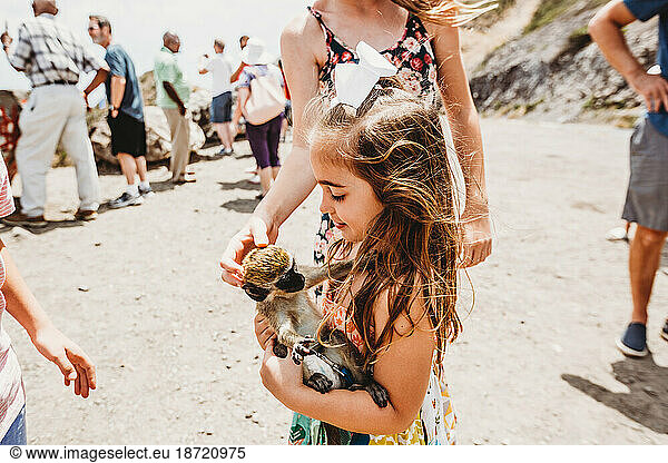 Young girl plays with monkey at tourist spot on island of St Kitts