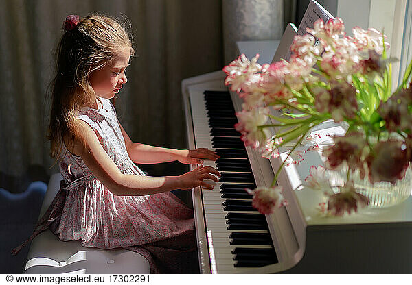 Young girl practicing piano at home. Beautiful scene. Indoor activity.