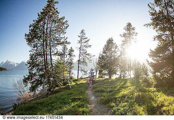 Young girl running down a trail on a sunny day in Grand Tetons