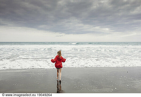 Young girl running towards the water at the beach