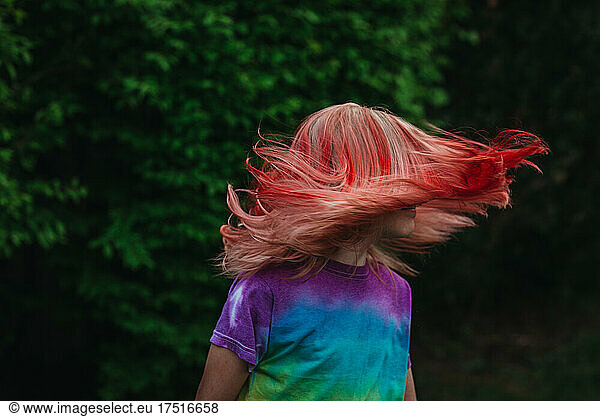 Young girl shaking hair outside with dyed red hair