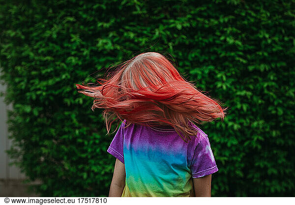 Young girl shaking head with dyed red hair outside