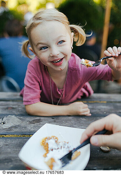 young girl sharing a treat at a picnic table