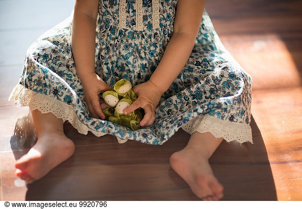 Young girl  sitting on floor  playing with toy  low section
