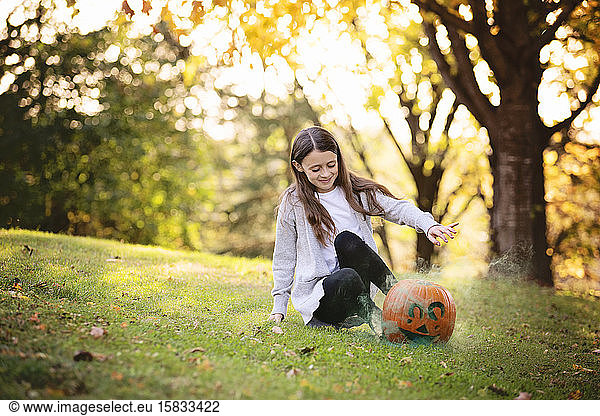 Young Girl Sitting Outside With Smoking Pumpkin in Fall