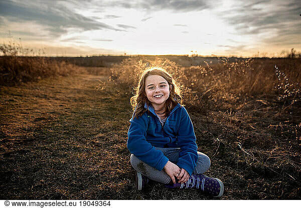 Young girl smiling in field at sunset