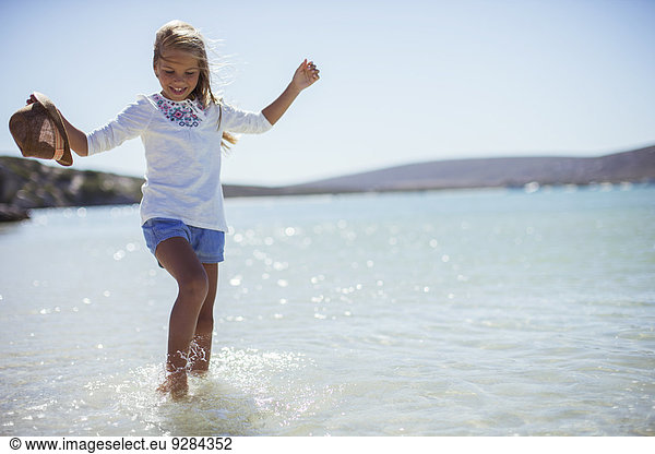 Young girl splashing in water on beach