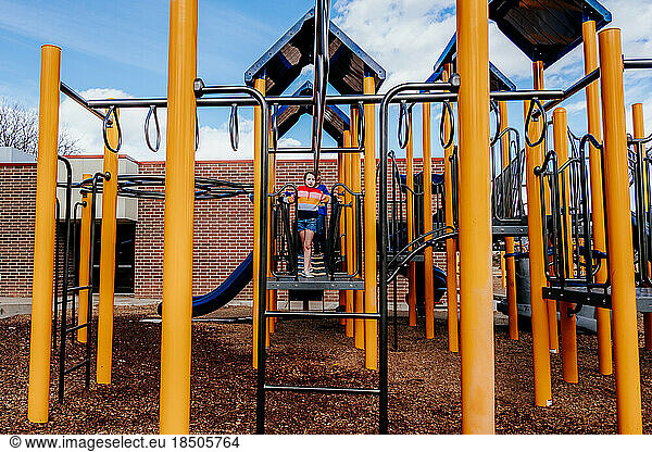 Young girl standing on top of play structure outside