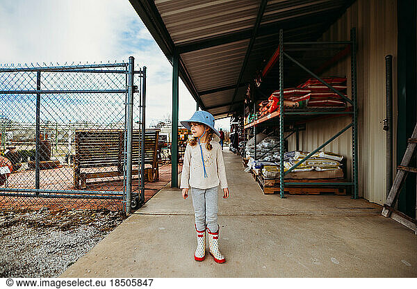 Young girl standing outside garden center wearing sun hat