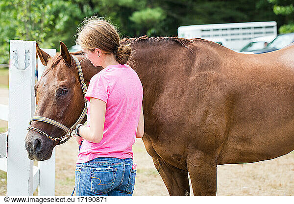 Young Girl standing with brown horse before an equestrian competition