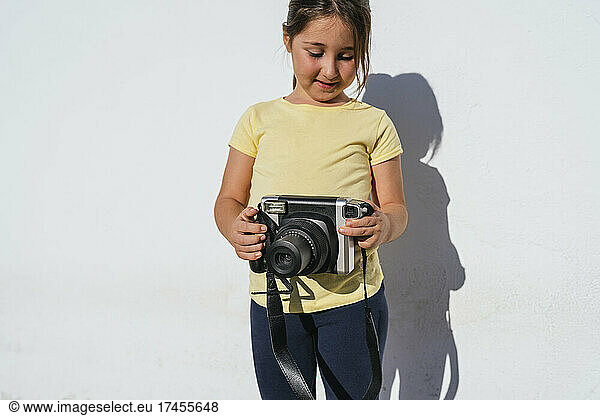 Young girl taking photo with instant camera