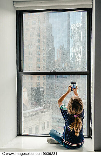 young girl taking picture of the view from her hotel room