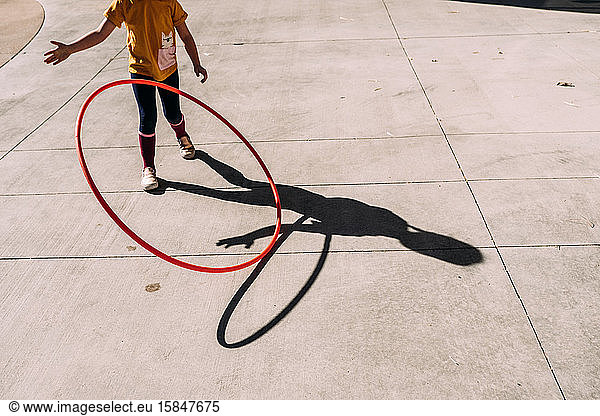 young girl throwing a hula hoop out side on a sunny day