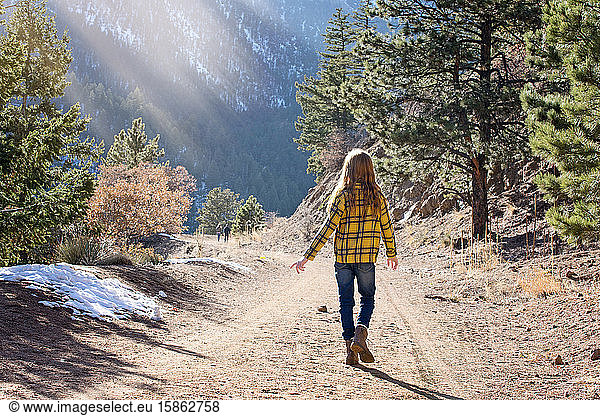 Young Girl Walking Down Mountain Path on Sunny Day