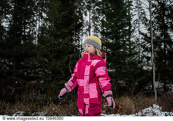 young girl walking in the snow in a snowsuit in winter