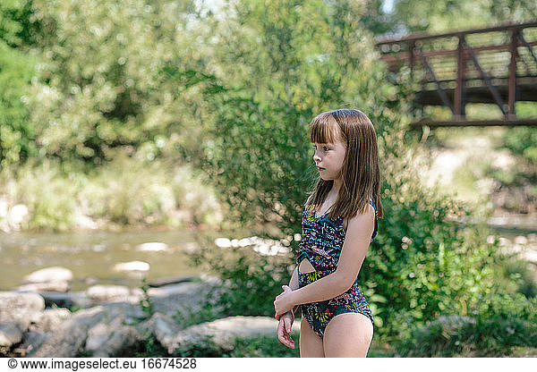 Young girl watching a small river on a summer day