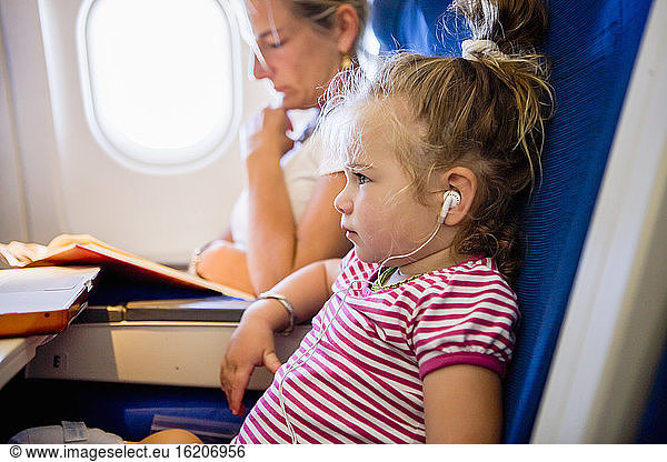 young girl wearing headphones on airplane