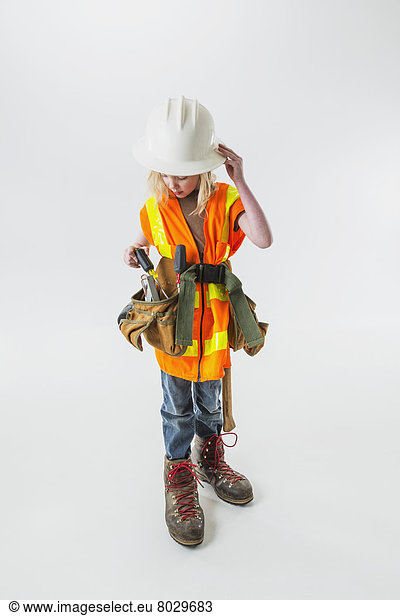 Young girl wearing oversized construction clothes and hard hat pulling a screwdriver out of her tool belt Anchorage alaska united states of america