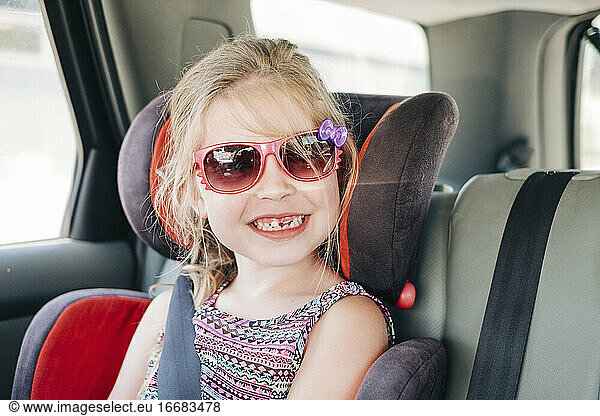 Young girl wearing sunglasses sitting in a car seat