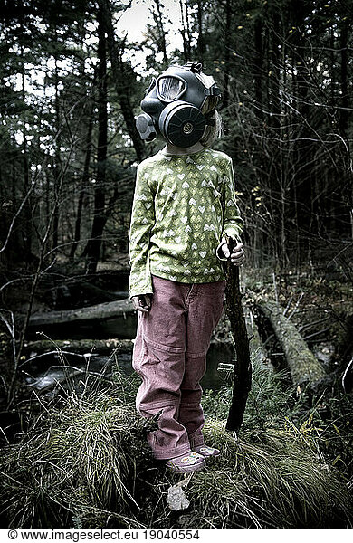 Young girl (5-6 Years) standing in the woods wearing gas mask  Maine.
