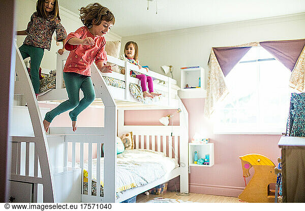Young girls having fun  playing  jumping off bunk bed in bedroom
