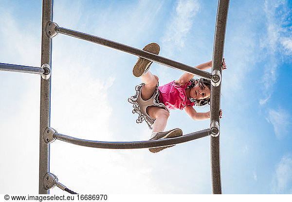 young girls looks straight down from a playground climbing structure