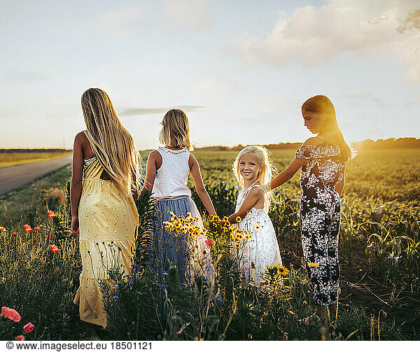 young girls walking through a field of wildflowers in summer