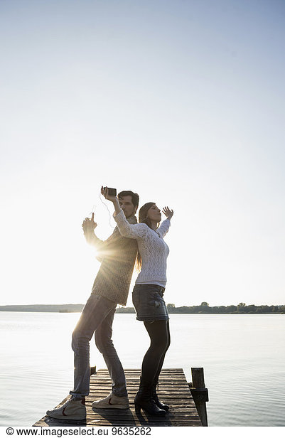 Young happy couple dancing jetty sunset
