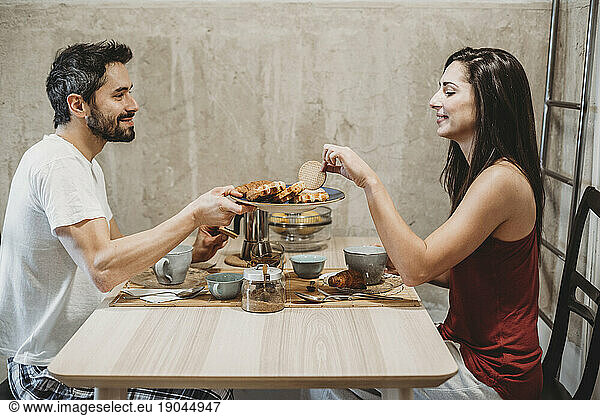 Young happy couple in love having breakfast at the kitchen table