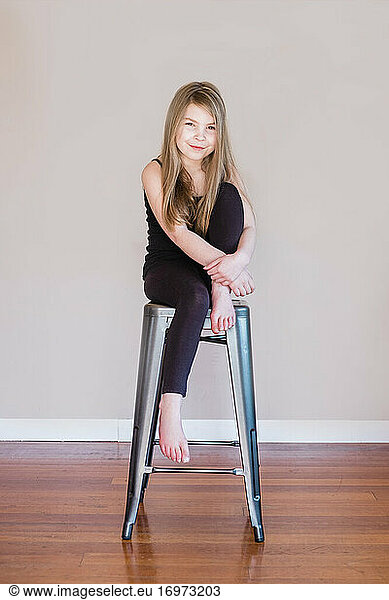 Young happy girl sitting on a stool inside