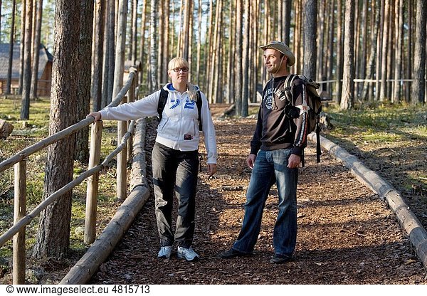 Young Happy Hiking Couple Standing on Wooden Boardwalk Stair in Forest
