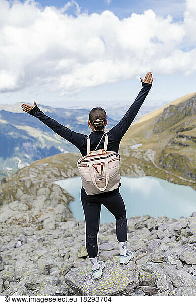Young hiker with arms raised on rock