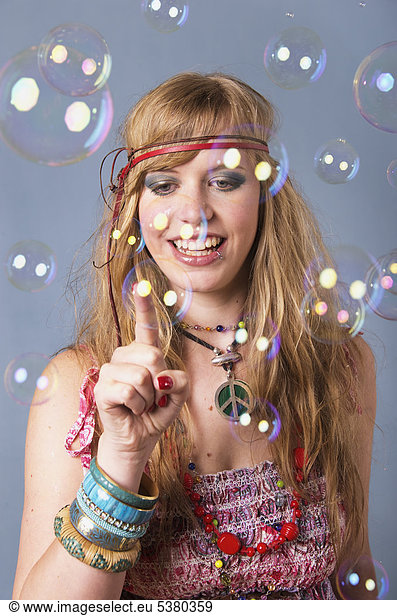 Young hippie woman with bubbles against grey background  smiling mouth