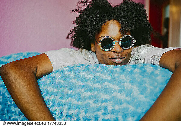Young hipster woman with sunglasses lying on blue blanket at home