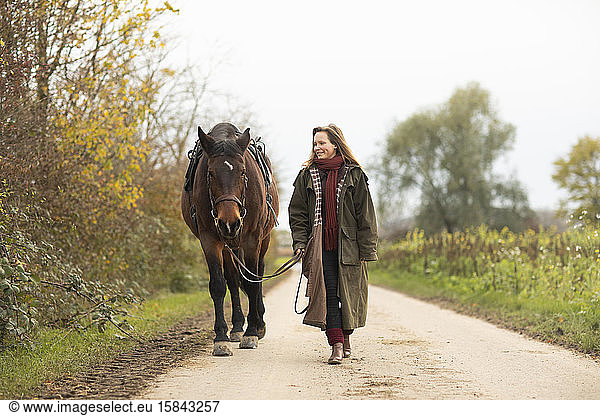 young horsewoman with a horse outeside walking