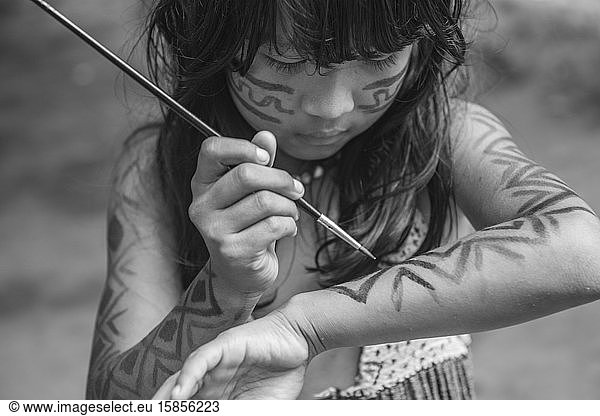 Young indigenous girl from Brazilian Amazon painting her body