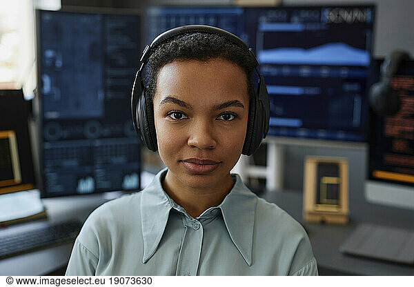 Young IT professional wearing wireless headphones in front of computers