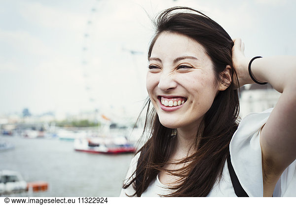 Young Japanese enjoying a day out in London  standing by the River Thames  London Eye in the background.