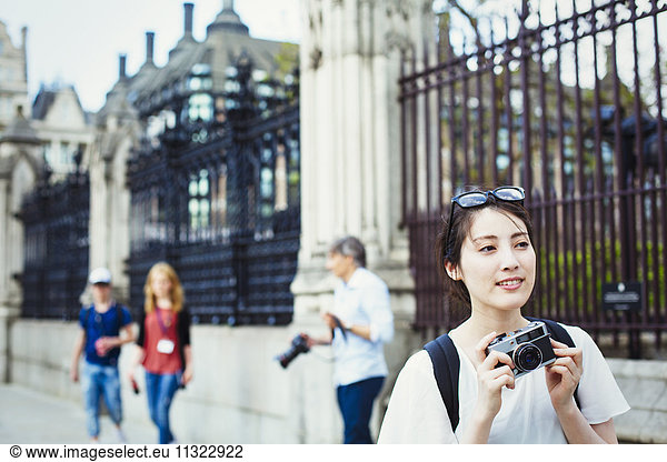 Young Japanese woman enjoying a day out in London  holing a camera.